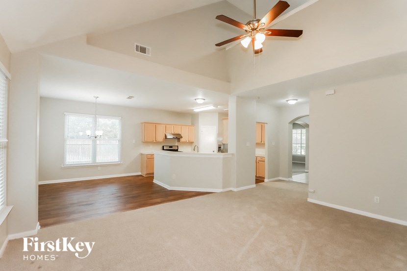 an empty living room and kitchen with a ceiling fan