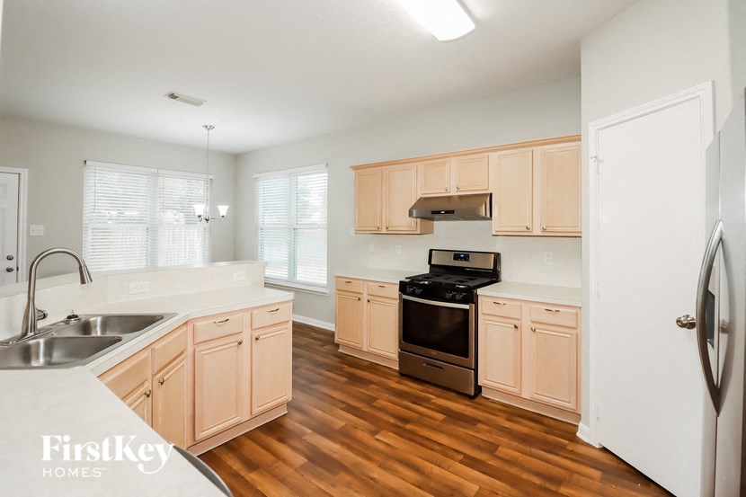 an empty kitchen with wooden floors and white cabinets