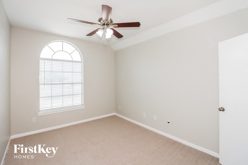 an empty bedroom with a ceiling fan and a window