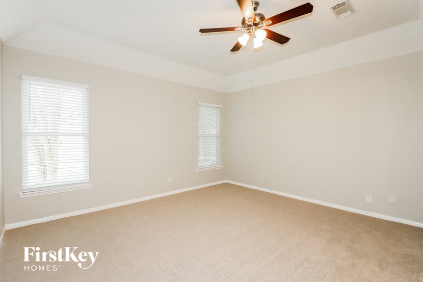an empty room with a ceiling fan and two windows