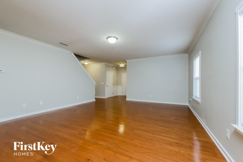 an empty living room with wood floors and white walls