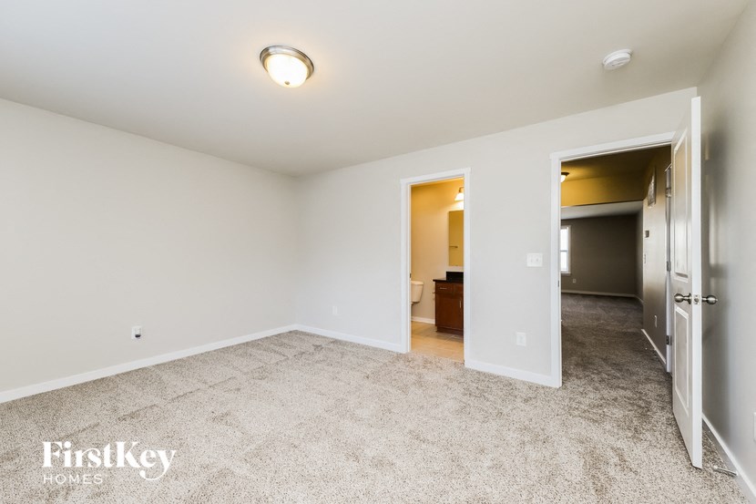 a bedroom with a carpeted floor and a door to a bathroom