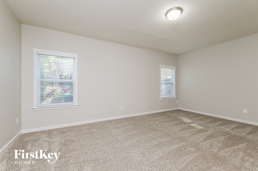 a spacious room with carpet and two windows