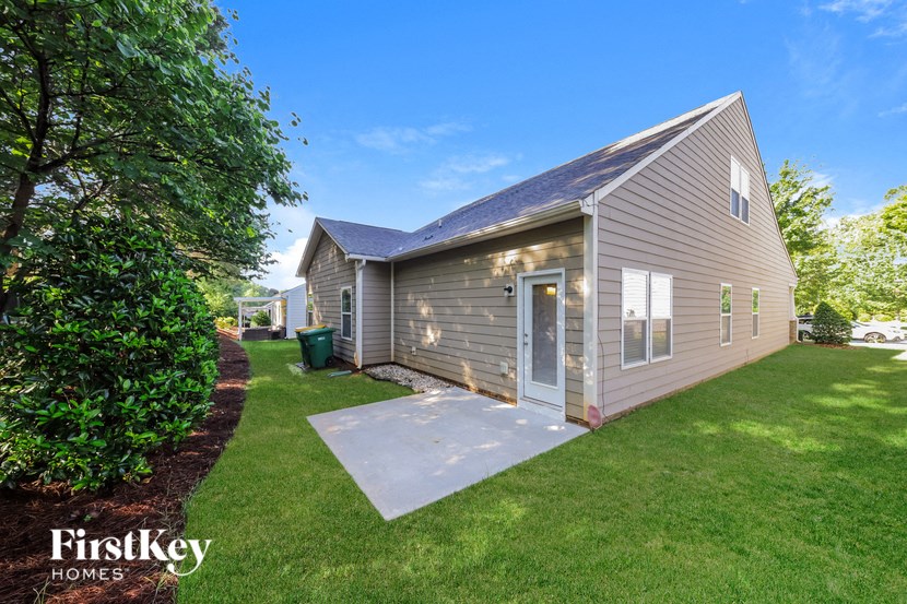 a small gray house with a yard and a driveway