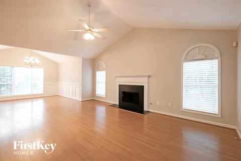 A spacious living room with a fireplace and a ceiling fan.