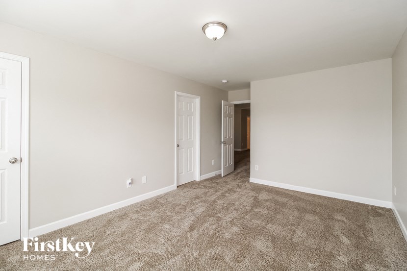 a empty living room with carpet and a door to a hallway