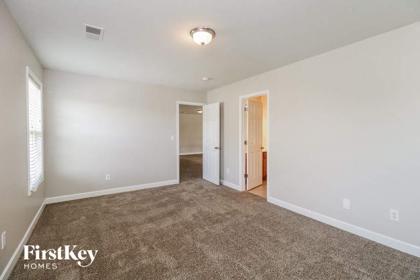 an empty living room with carpet and a door to a hallway