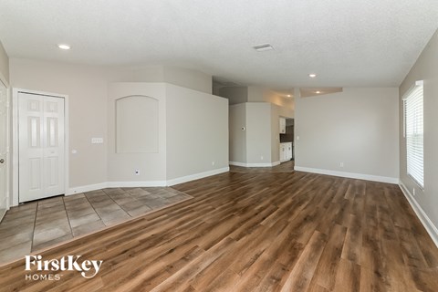 A spacious room with wooden flooring and white walls, part of a house by FirstKey Homes.