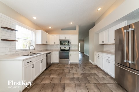 A modern kitchen with white cabinets and a tile floor.