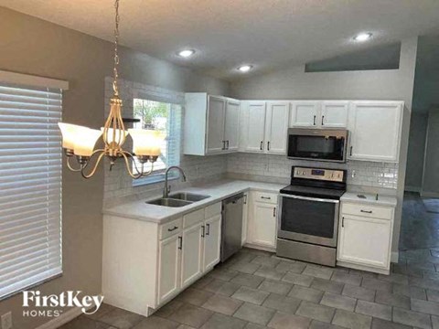 A kitchen with white cabinets and a stove top oven.