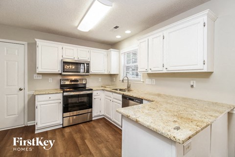 a kitchen with white cabinets and a marble counter top