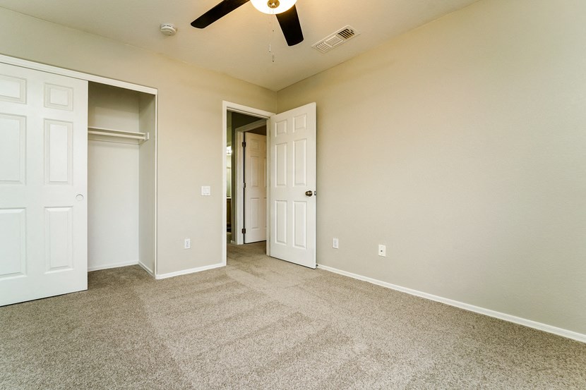 an empty living room with carpet and a ceiling fan