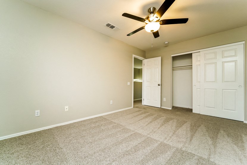 an empty living room with a ceiling fan