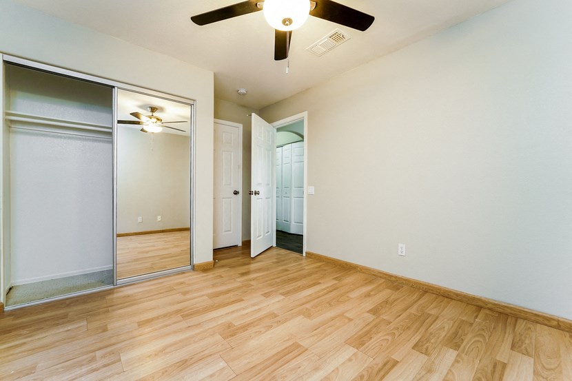 an empty living room with wood flooring and a ceiling fan