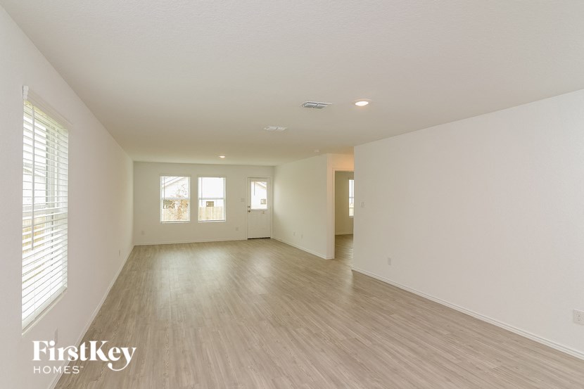 a spacious living room with white walls and wood floors
