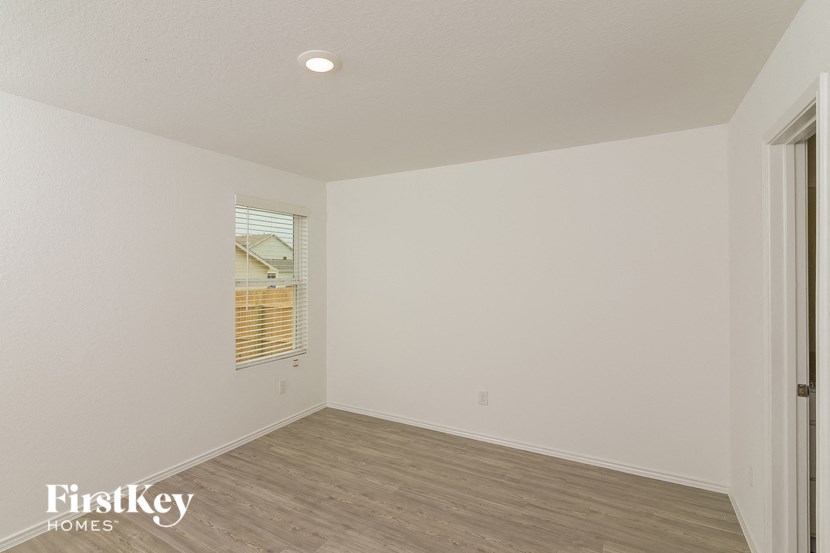 a bedroom with white walls and wood flooring and a window
