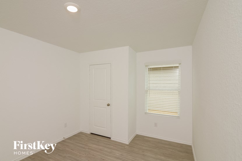 a bedroom with white walls and a white door and a window
