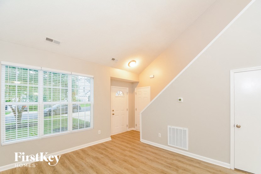 an empty living room with a large window and a door to a hallway