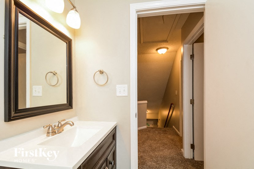 a bathroom with a sink and a mirror      and a hallway