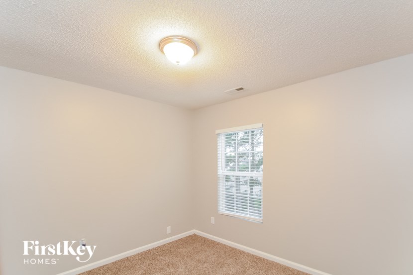 a bedroom with a large window and a carpeted floor