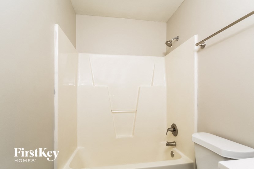 a white bathroom with a white toilet and a bath tub