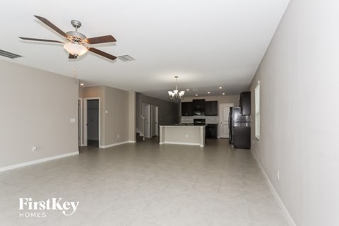 A spacious room with a ceiling fan and a chandelier.