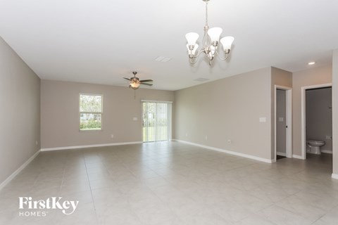 A spacious room with a chandelier, ceiling fan, and a window.