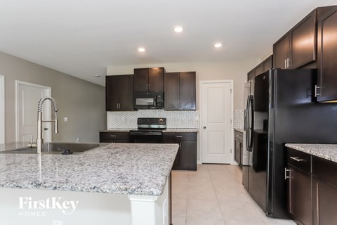 A kitchen with granite countertops and black appliances.
