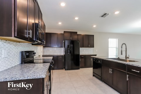 A kitchen with a black refrigerator and a FirstKey Homes logo.