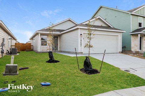 three young trees are planted in the front yard of a house