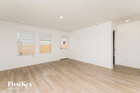 A room with wooden flooring and a door on the right side.