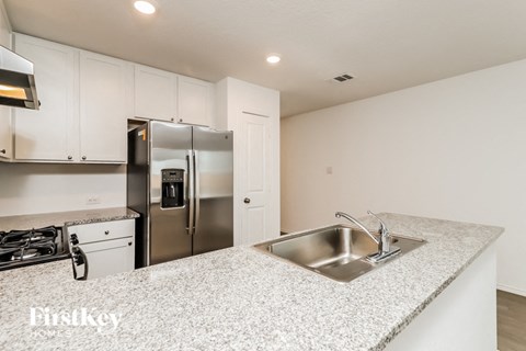 A kitchen with a stainless steel refrigerator and a granite countertop.