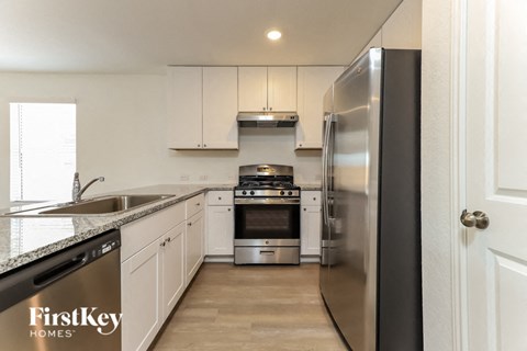 A modern kitchen with a stainless steel refrigerator and white cabinets.