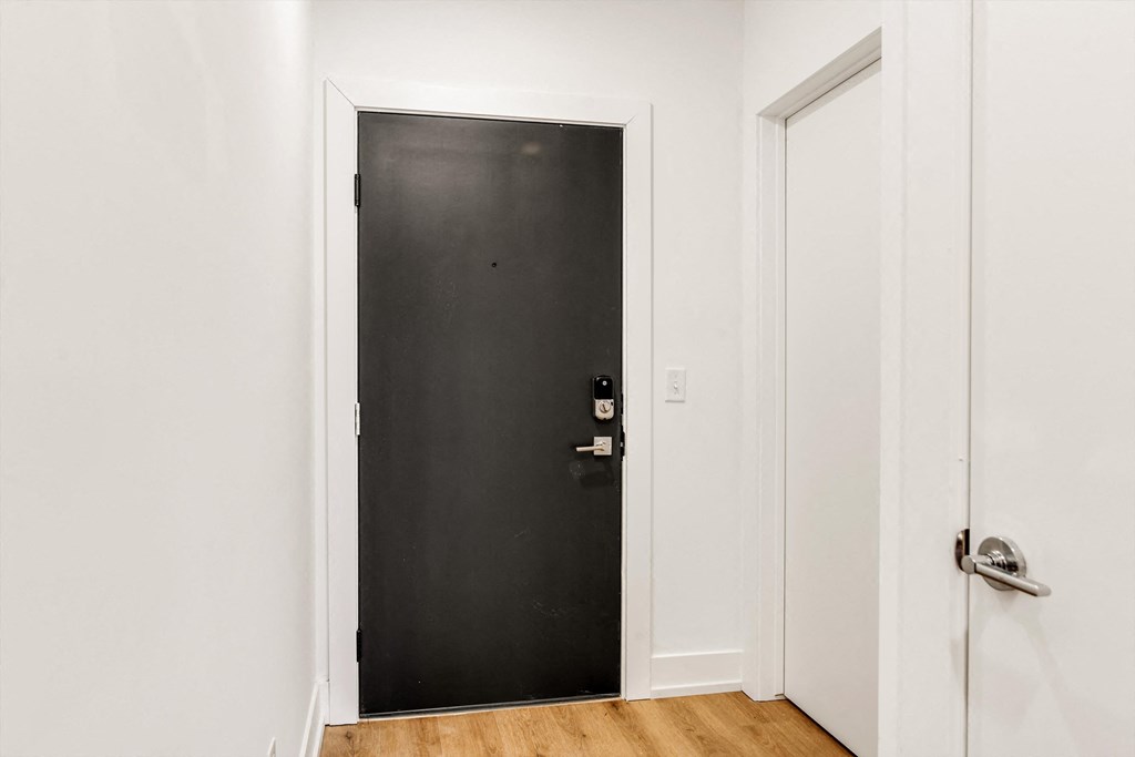 a black door in a room with white walls and a wooden floor