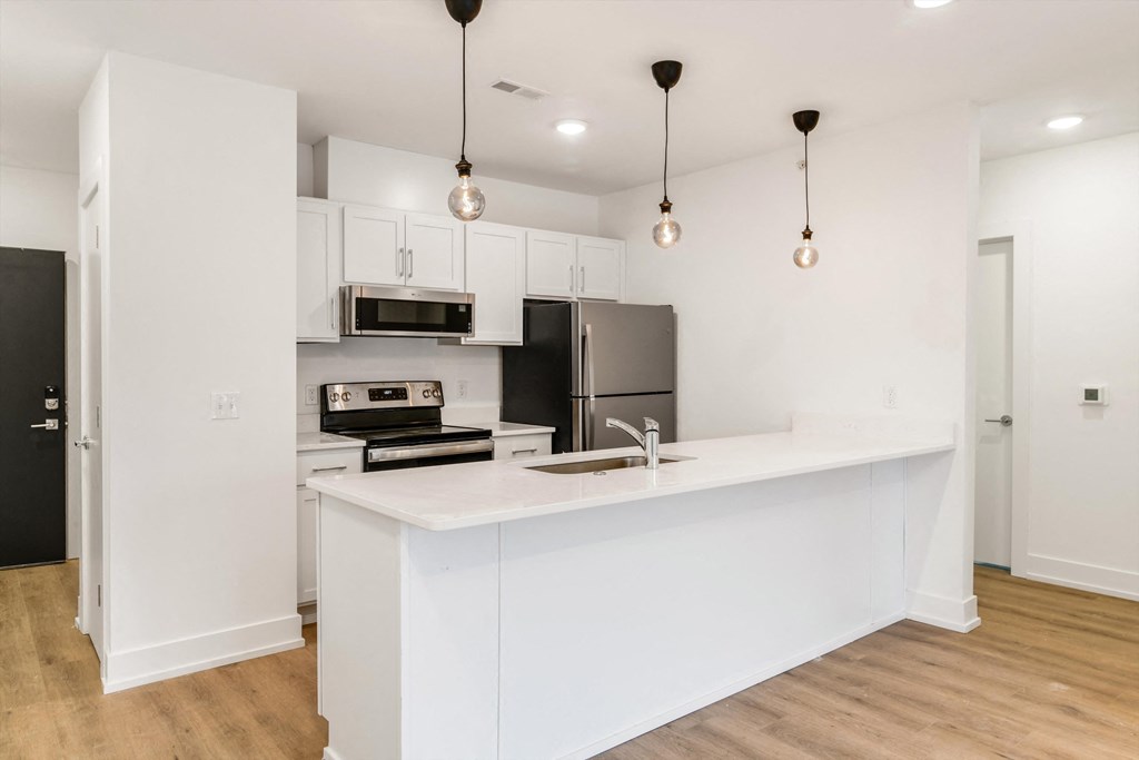 a white kitchen with an island and a stainless steel refrigerator