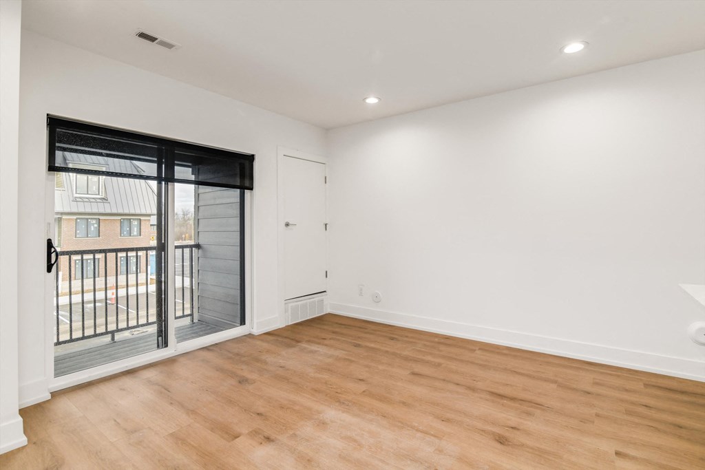 an empty living room with a sliding glass door to a balcony