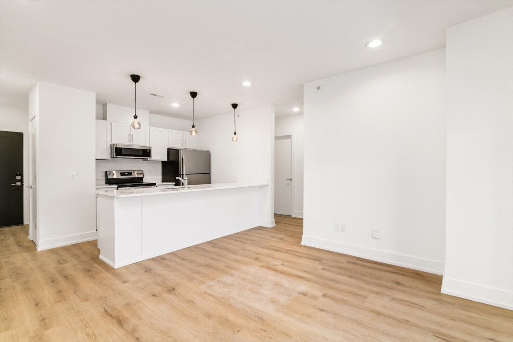 an empty living room and kitchen with white walls and wood floors
