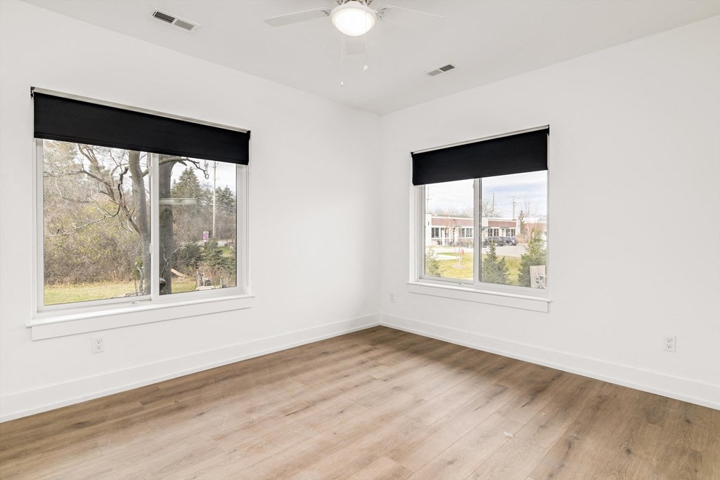 a living room with wood floors and two windows