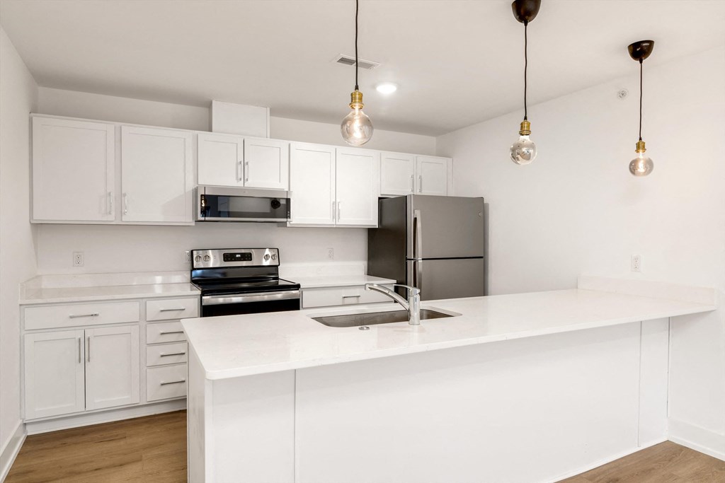 a white kitchen with stainless steel appliances and white counter tops