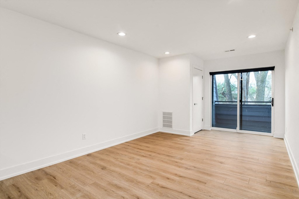 a living room with white walls and a door to a balcony