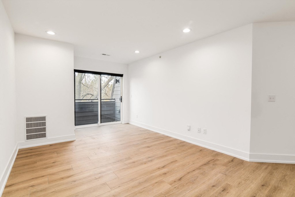 a living room with white walls and wood floors and a sliding glass door
