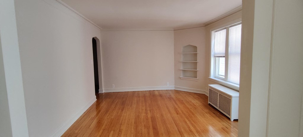 a room with white walls and a wooden floor and a window
