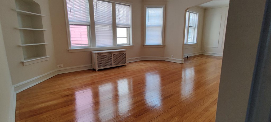 an empty living room with wooden floors and windows