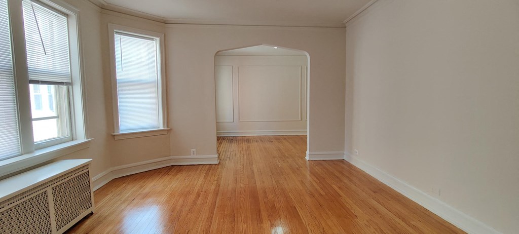 a living room with a hard wood floor and a door to a hallway