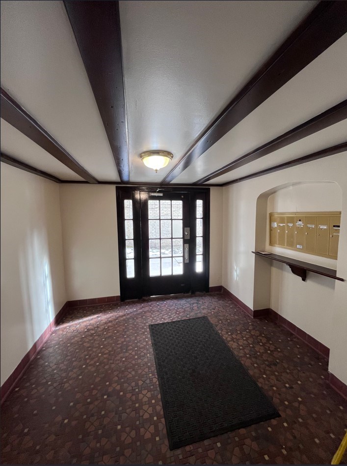 A hallway with a black mat on the floor and a door at the end.