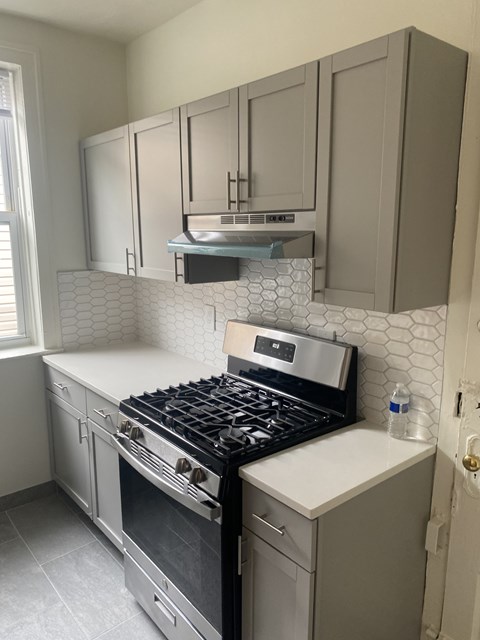 A kitchen with a black stove top oven and a white counter top.