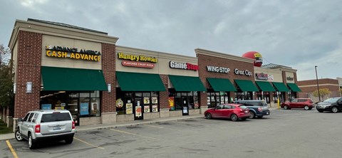 the front of a shopping center with cars parked in a parking lot