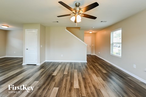 A spacious room with wooden floors and a ceiling fan.