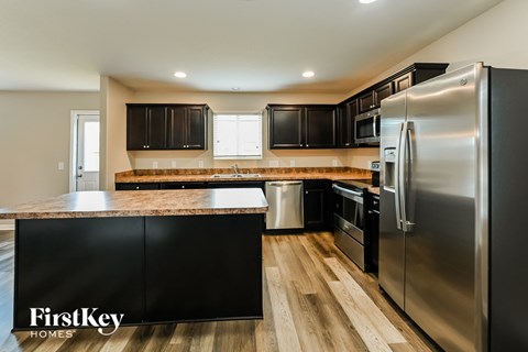 A kitchen with a stainless steel refrigerator and black cabinets.