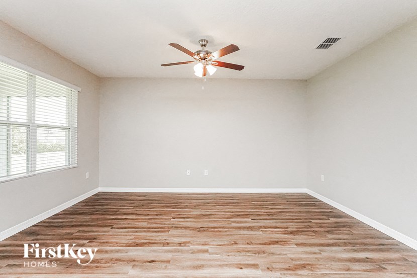 A room with a ceiling fan and wooden flooring.